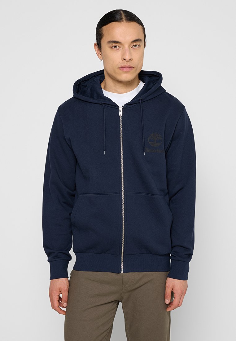 Felpa con zip color navy realizzata in cotone, dotata di tasca frontale, cappuccio con cordino e piccolo logo sul petto. Presenta polsini e orlo a costine.