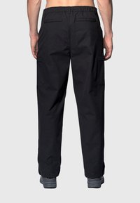 Zwarte cargobroek van lichtgewicht stof met een elastische tailleband, voorzien van twee achterzakken en zijcargozakken.