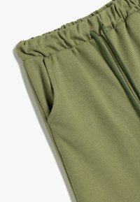 Olivgrüne Jogginghosen mit strukturiertem Finish, elastischem Bund, Kordelzugakzent und seitlichen Taschen für zusätzliche Funktionalität.