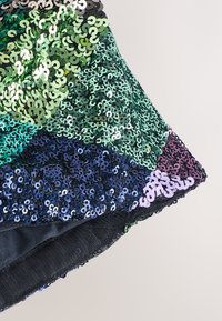 Tissu multicolore à paillettes en vert, noir et violet, présentant un design patchwork avec des textures variées et une couche arrière lisse.