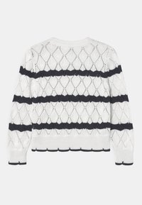 White knitted sweater featuring a diamond pattern with navy horizontal stripes. Ribbed cuffs and hem with scalloped edges.