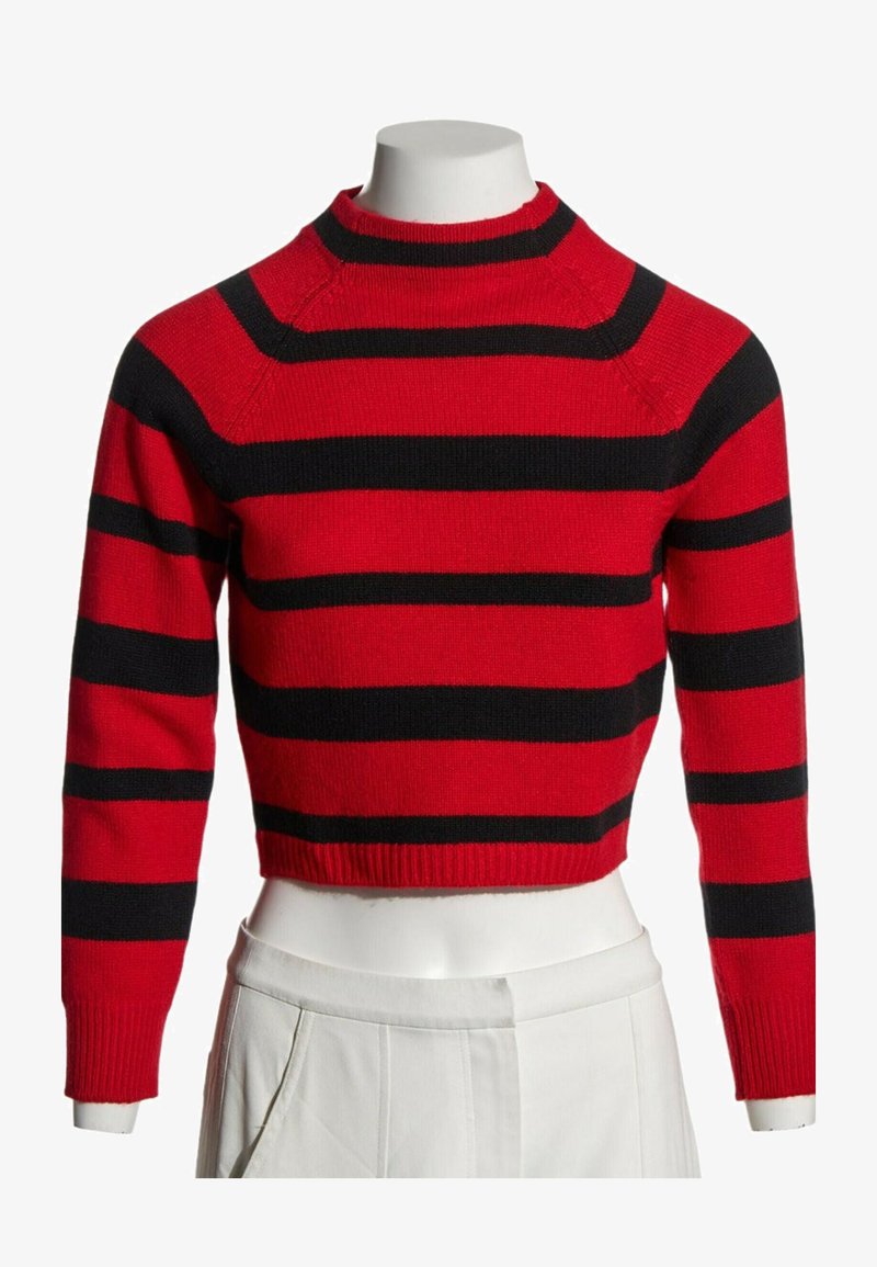 Pull court rouge à rayures horizontales noires présenté sur un mannequin buste portant un pantalon blanc.