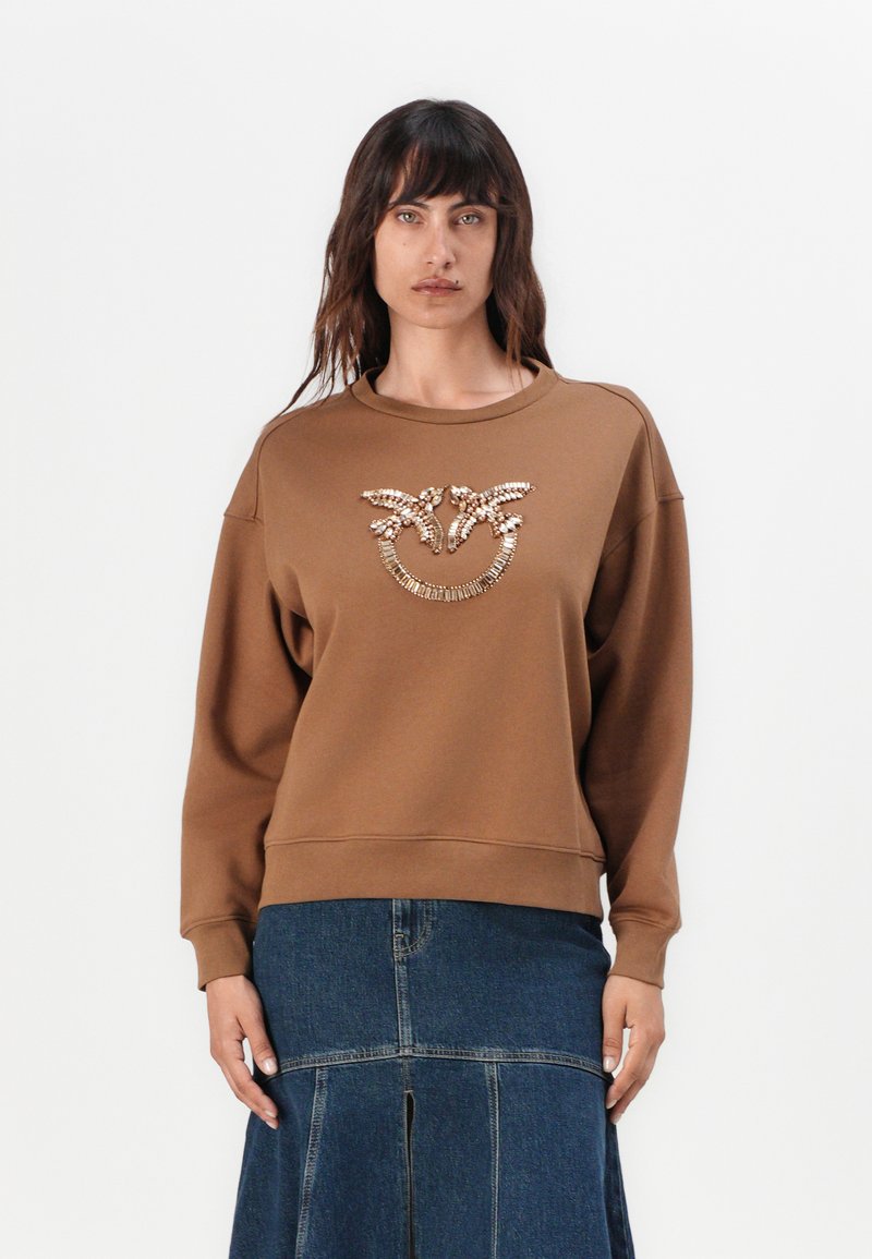 Bruine sweatshirt met een ronde halslijn en verlaagde schouders, voorzien van decoratieve gouden versieringen in een bloemmotief op de voorkant.