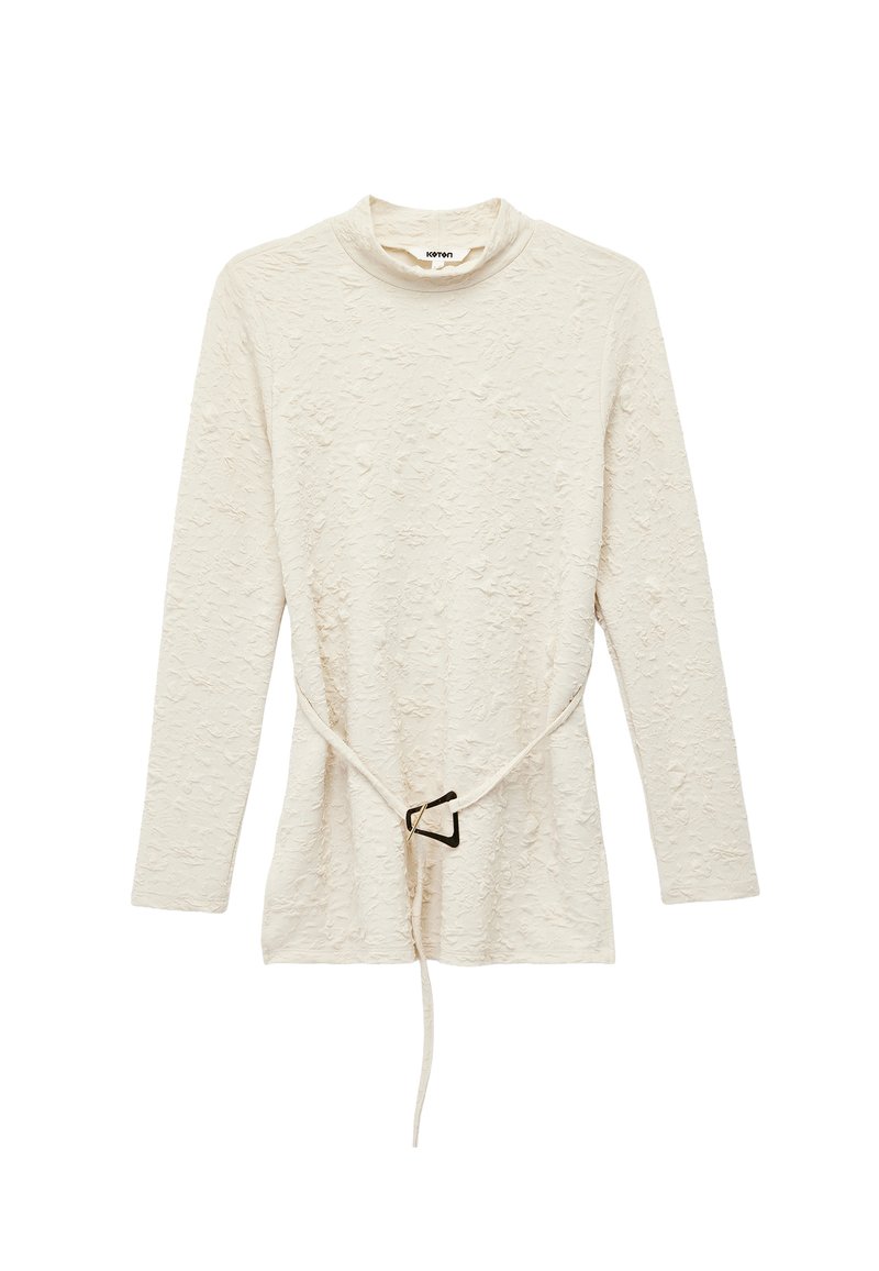 Langærmet cremefarvet bluse med struktur, høj krave og et tyndt bælte med en geometrisk spænde i taljen.