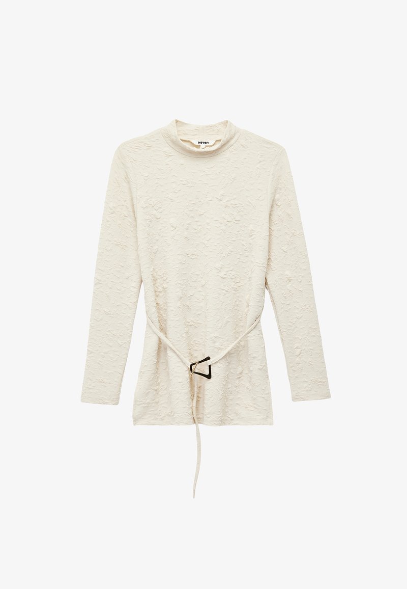 Langærmet cremefarvet bluse med struktur, høj krave og et tyndt bælte med en geometrisk spænde i taljen.