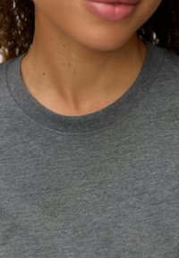 Tricou gri din bumbac cu decolteu rotund, având o textură moale, cu un design simplu și cusături vizibile în jurul gâtului.