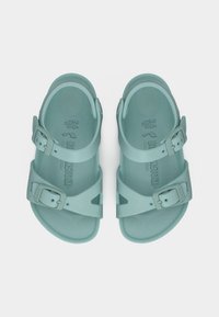 Ανοιχτό μπλε πλαστικές σαγιονάρες με δύο ρυθμιζόμενα λουριά με αγκράφες και λεπτομέρειες με εκκοπές, διαθέτουν εσωτερική σόλα με ανάγλυφο σχήμα και λεία υφή.