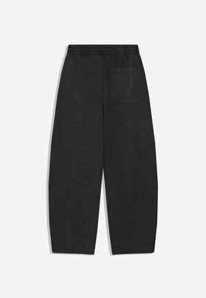 Schwarze locker sitzende Hose mit elastischem Bund und einer einzelnen aufgesetzten Gesäßtasche, flach auf weißem Hintergrund dargestellt.