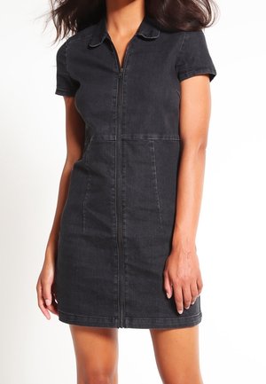 Czarna sukienka z denimu z krótkimi rękawami i zapięciem na zamek z przodu. Posiada spiczasty kołnierzyk, boczne kieszenie i dopasowany fason.