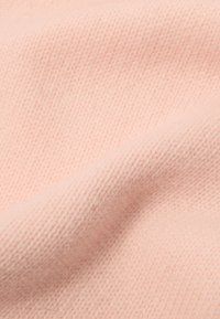 Tissu doux et texturé dans une teinte rose pâle, présentant un motif en maille fine avec des variations subtiles de profondeur et d'épaisseur.