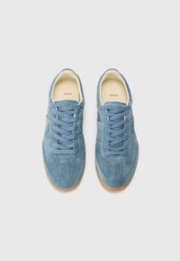 Sneakers in camoscio blu chiaro con punta arrotondata, design con lacci e suola in gomma naturale. L'interno ha una fodera beige e il logo del marchio.