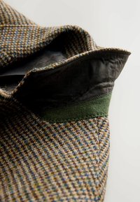 Wool blend fabric with a textured brown and blue houndstooth pattern. Features a dark green felt accent and a smooth black lining.