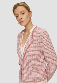 Roze textuurblazer met een rasterpatroon, contrasterende afwerking en een getailleerde pasvorm. Voorzien van een reverskraag en twee voorzakken.