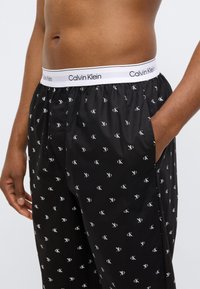 Μαύρα βαμβακερά μποξεράκια με λευκό ελαστικό ζωνάρι στη μέση που φέρει το λογότυπο "Calvin Klein" και επαναλαμβανόμενο μικρό λευκό μοτίβο 'CK'.