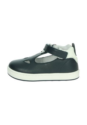 Scarpetta bianca e nera per bambino con dettagli ritagliati, strap a velcro alla caviglia e suola in gomma bianca su sfondo bianco semplice.