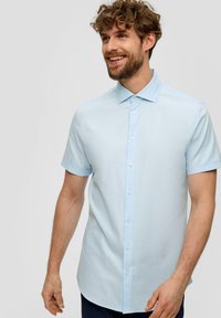 Lichtblauw kortemouwenshirt met een knoopsluiting kraag, uitgevoerd in een fijne textuur en met een rechte zoom. De knopen zijn wit.