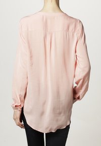 Vaaleanpunainen pitkähihaisyntä paita, jolla on sileä, silkkinen rakenne, pyöreä helma ja pleatit selässä. Varustettu napillisilla hihansuilla ja rentoa istuvuutta.