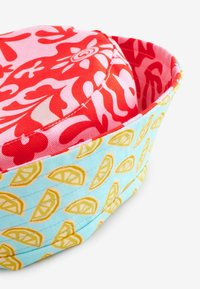 Colorful fabric basket with a red floral pattern on the inside and a light blue exterior featuring yellow lemon slices. Soft texture.