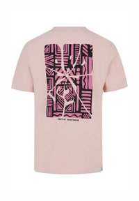 Svijetlo ružičasta majica s crnom i ružičastom grafikom na leđima, koja prikazuje apstraktne oblike i tekst "PROTEST SPORTSWEAR."