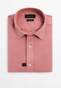 Chemise en lin rose clair pliée, boutonnée, col large et deux boutons visibles sur la patte de boutonnage, indiquée comme coupe régulière.