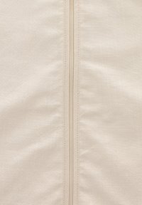 Beiger Stoff mit glatter Textur, ausgestattet mit einem zentralen Reißverschluss und passender Naht, die ein sauberes und schlichtes Design schaffen.