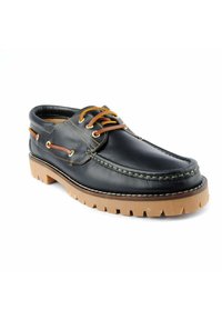 Zapato de barco de cuero negro con acentos marrones, diseño de cordones y suela de goma texturizada. Presenta una puntera cosida y ojales en tono dorado.