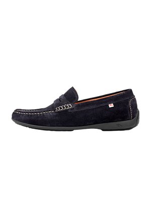 Mocassin pour homme en daim noir avec couture blanche, semelle en caoutchouc et petite étiquette en tissu rouge et blanc sur le côté.