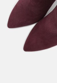 Burgundské semišové lodičky s designem špičaté špičky. Hladká textura a čisté linie, které ukazují elegantní siluetu.
