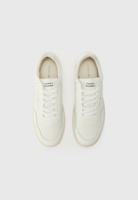 Paire de baskets blanches Tommy Hilfiger avec lacets, logo sur la languette et le côté, présentée en vue de dessus sur un fond clair.