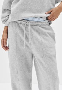 Graue Sweatpants mit elastischem Bund, verstellbarem Kordelzug und Seitentaschen; aus weichem Baumwollmischgewebe gefertigt.
