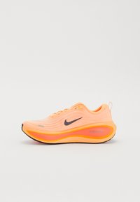 Leuchtend orangefarbene Nike-Laufschuhe mit schwarzem Swoosh, dickem gepolstertem Sohlen und "ZoomX"-Markierung an der Seite, im rechten Profilansicht gezeigt.