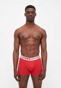 Rote Boxershorts aus dehnbarem Stoff, mit einem weißen elastischen Bund, der das Logo "JACK & JONES" und horizontale Streifenakzente zeigt.
