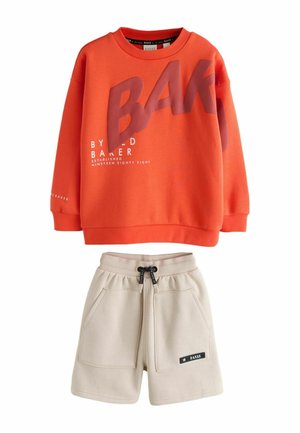Orange long-sleeve sweatshirt with large "BAKER" text and beige drawstring shorts with front pockets and black label on left leg.