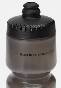 Bottiglia d'acqua trasparente grigia con tappo a vite nero e impugnatura texturizzata. Presenta un testo stampato: "ATTACCA A D.S. MENTRE LA STRADA SALE."