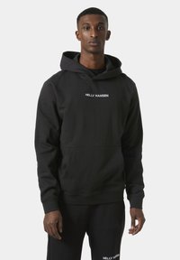 Black hoodie made of cotton blend with a front pocket; features white embroidered logo "HELLY HANSEN" on the chest and a drawstring hood.