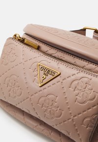 Rosa vadderad väska i syntetläder med guldtriangellogo, dragkedja och präglat mönster, med slät yta och sömnadselement.