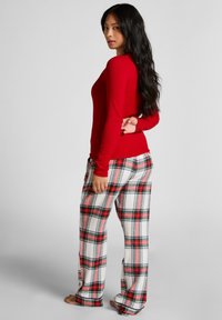 Rode long sleeve top gecombineerd met wit en rood geblokte broek. De top heeft een aansluitend ontwerp; de broek is los met een ruitpatroon en afgeknipte enkels.
