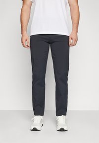 Marineblauwe broek van lichtgewicht stof, met een rechte pasvorm, een tailleband, voorzakken en gecombineerd met witte basketbalschoenen.