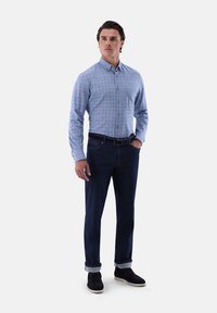 Hellblaue karierte Button-Down-Bluse, dunkle Denim-Jeans und schwarze Wildleder-Ankle-Boots. Die Bluse hat einen Kragen und lange Ärmel.