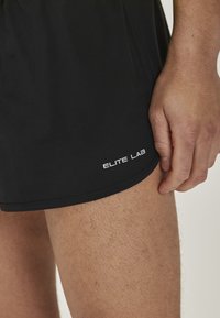 Sorte træningsshorts lavet af letvægtsstof, med et logo "ELITE LAB" i hvid, glat tekstur og skræddersyet pasform.