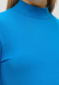 Blauw coltrui gemaakt van soepel materiaal, met een aansluitende pasvorm en gemiddelde dikte, die een levendige, uniforme kleur toont.