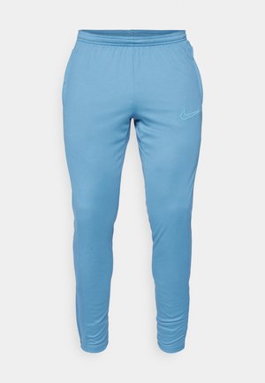 Pantalones de chándal Nike de color azul claro con cintura elástica, ajuste slim y acento del logo cerca de la cadera izquierda. Tela suave sin patrones visibles.