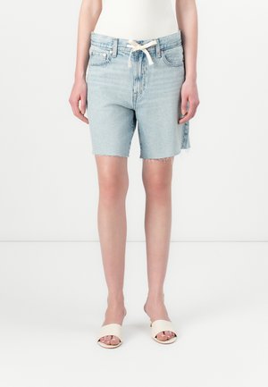 Light blue denim shorts with frayed edges, a high waist, and a drawstring. Worn with neutral-colored open-toe slides.