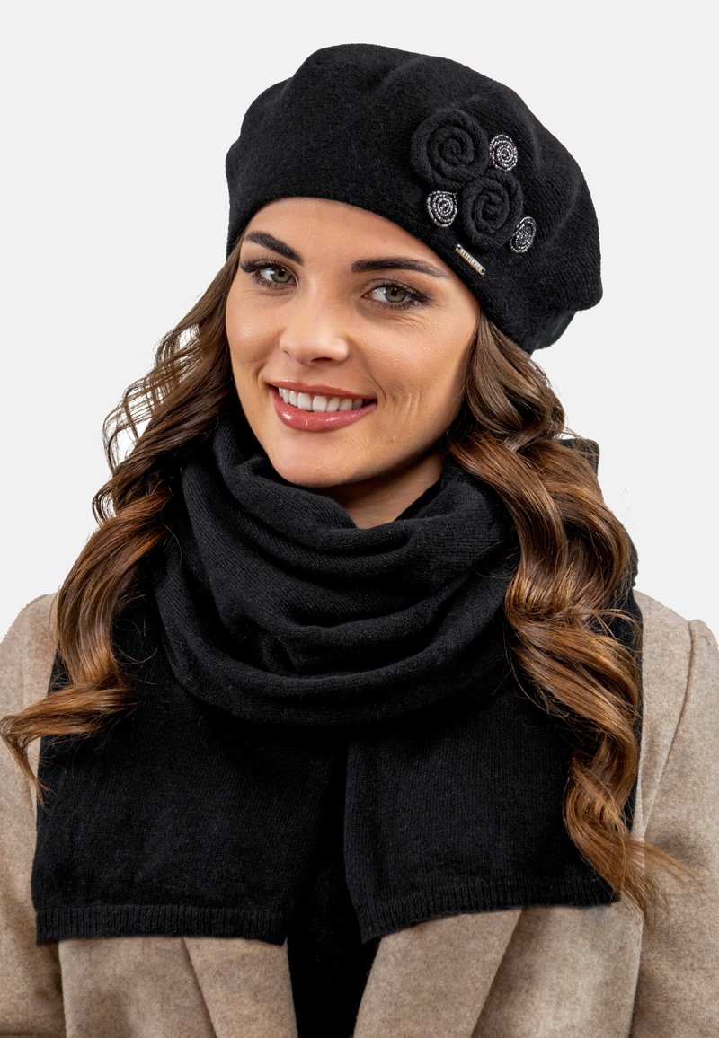 Beret negro de lana con adornos de flores; combinado con una bufanda negra de lana a juego, ambos exhibiendo una textura suave y un diseño en capas.