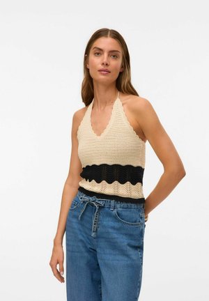 Haut en crochet bandeau beige avec un design noir en forme de vagues à la taille. Le tissu est texturé, associé à un jean en denim taille haute.