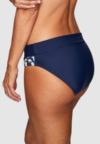 Mörkblå hög midja bikiniunderdel med ett mönstrat sidopanel som har vita former, tillverkad av ett mjukt, stretchigt material.