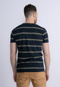 Marinrandig t-shirt med gula och vita horisontella ränder, korta ärmar och rund hals, tillverkad av bomullsmaterial. Lämplig för vardagsbruk.