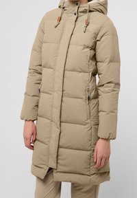 Beige vadderad jacka med huva, utrustad med tryckknappar och dragkedja, sidofickor och en förlängd design för värme och skydd.