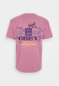 Růžové bavlněné tričko s grafickým potiskem na zádech obsahujícím motýly a text, krátké rukávy a volný střih.