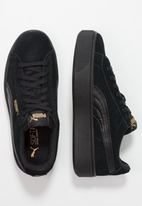 Sneakers in suede nero con suole in gomma nera piatte, lacci rotondi e logo del marchio dorato. Presentano un pannello laterale testurizzato per un tocco di design in più.